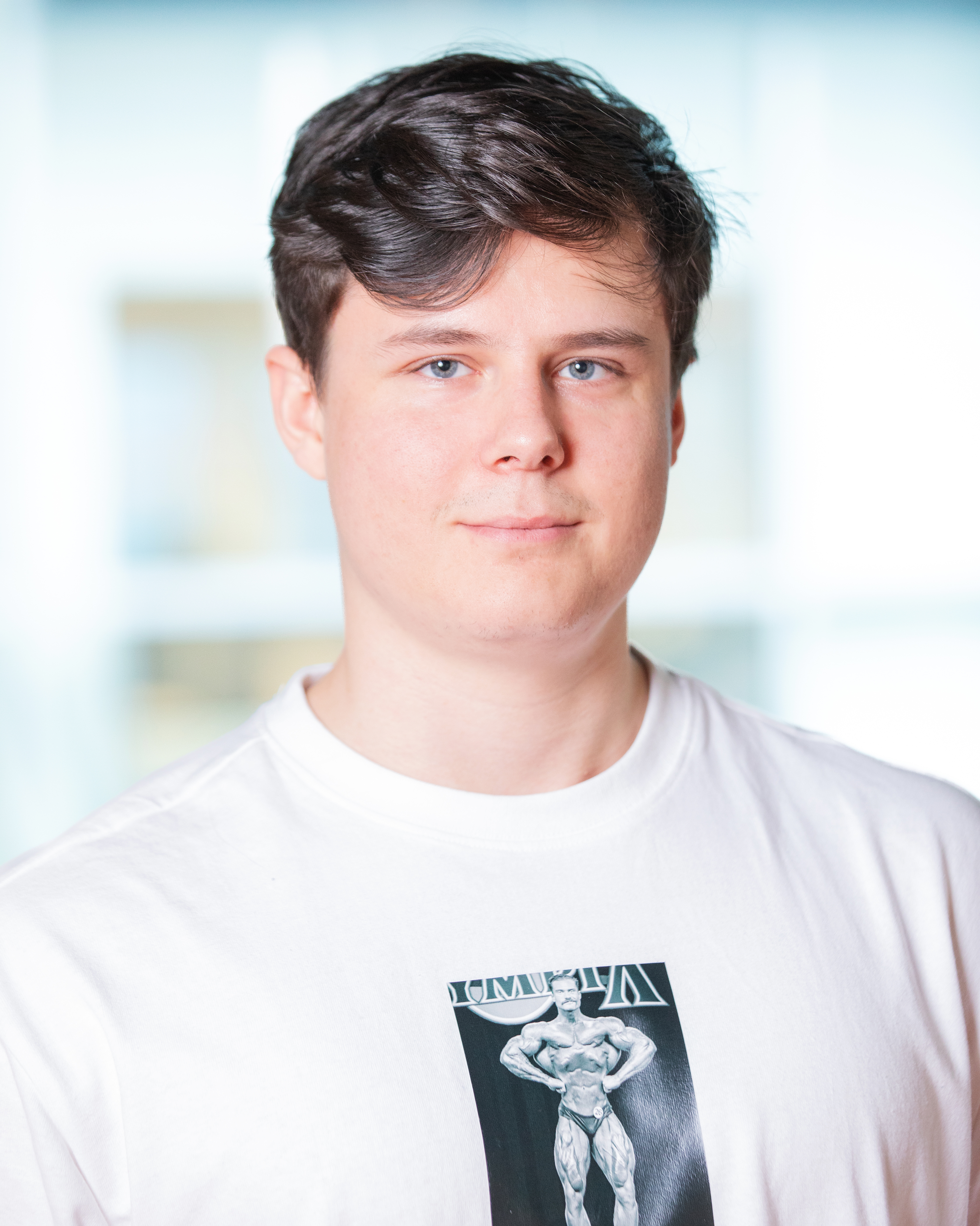 Wolfgang Bubberman smiling in a portrait photo wearing a white shirt with Chris Bumstead on it.